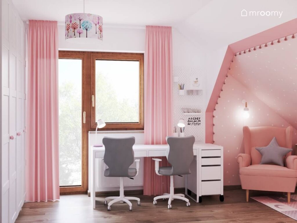 Strefa nauki w pokoju dwóch dziewczynek a w niej duże biurko z szarymi fotelami organizery ścienne oraz różowe zasłony
