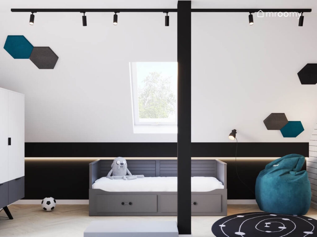 Biały skos z sześciokątnymi panelami i czarna ścianka kolankowa w poddaszowym pokoju chłopca z ciemnym łóżkiem