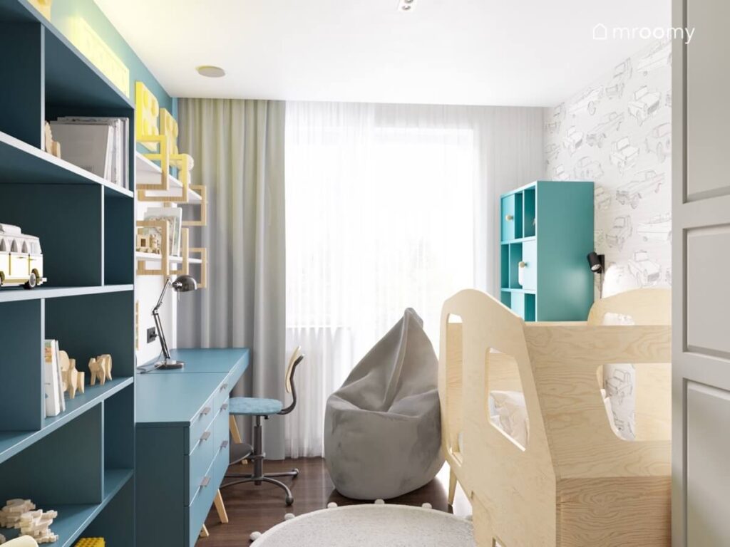 Jasny pokój dla chłopca a w nim niebieskie meble drewniane łóżko w formie przyczepy kempingowej oraz szara pufa