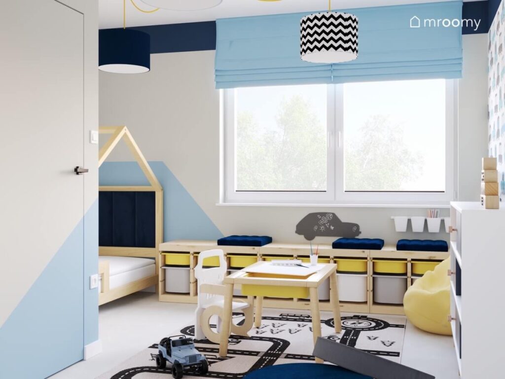 Szaro błękitny pokój dla chłopca a w nim drewniane meble dywan z drogą oraz granatowe dodatki