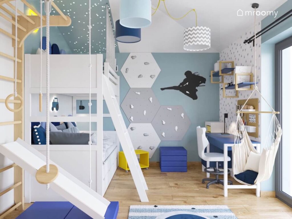 Biało błękitny poddaszowy pokój dla chłopca z białym łóżkiem piętrowym panelami wspinaczkowymi oraz naklejką ninja