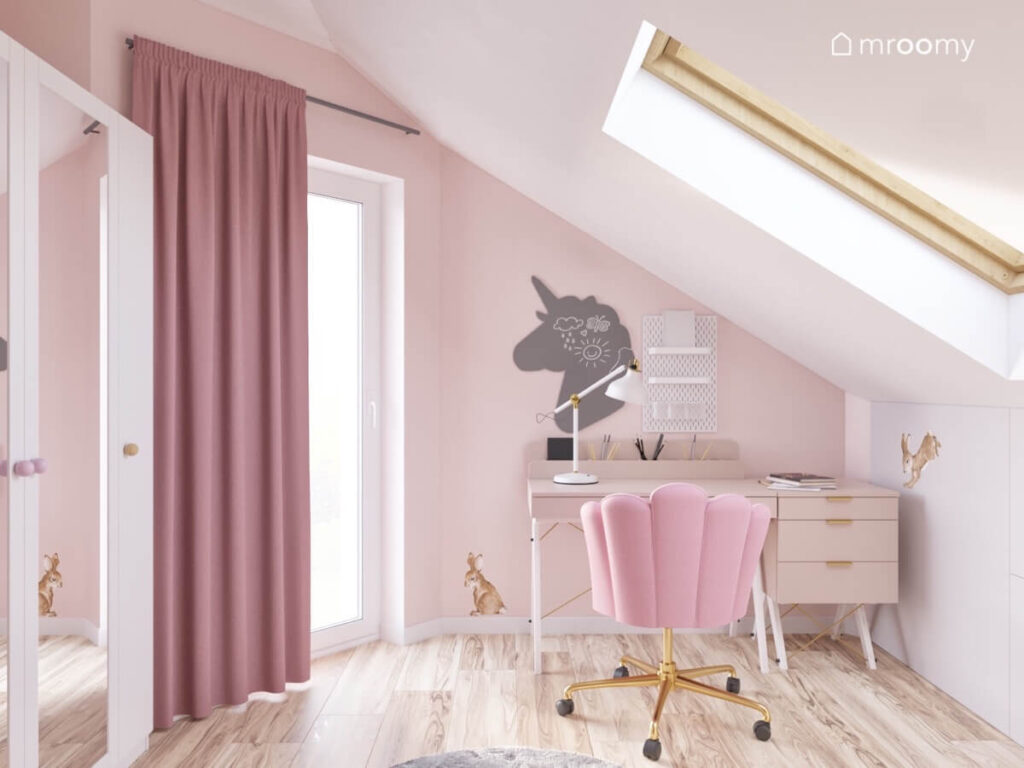 Poddaszowy pokój dla kilkuletniej dziewczynki a w nim różowe ściany biały sufit biurko z tapicerowanym krzesłem i tablica kredowa w kształcie jednorożca