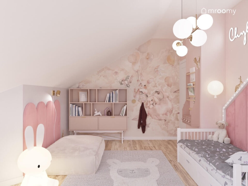 Różowo szaro biały pokój na poddaszu dla dziewczynki a w nim tapeta w króliki białe łóżko domek regał oraz dywan z lamą
