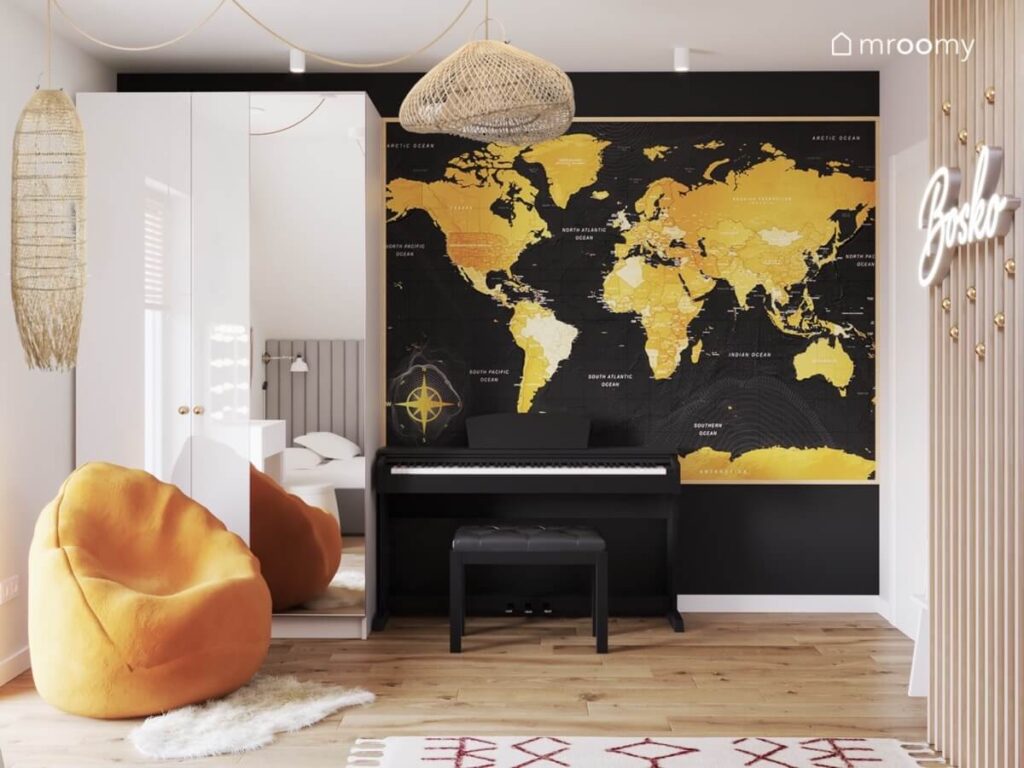 Biała szafa z lustrzanym frontem a obok pianino a na ścianie wielkoformatowa złota mapa świata w biało czarnym pokoju nastolatki