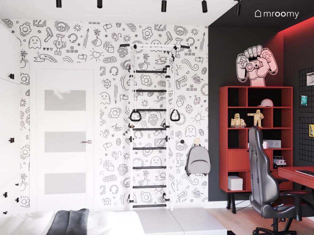 Ściana pokryta młodzieżową tapetą a na niej biało czarna drabinka gimnastyczna w pokoju chłopca