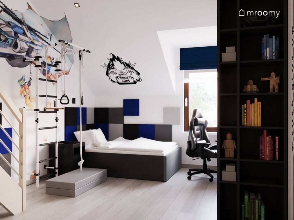 Jasny poddaszowy pokój dla nastolatka z ciemnoszarym łóżkiem kwadratowymi panelami na ścianach naklejkami gamingowymi i lego oraz drabinką gimnastyczną