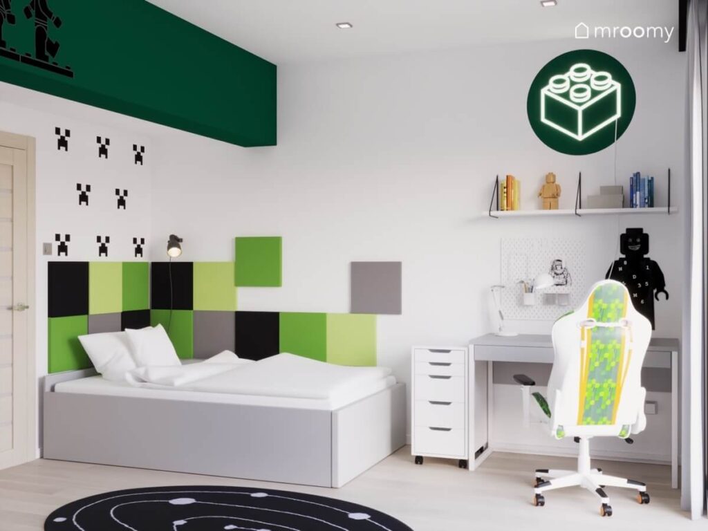 Jasne łóżko z szarymi i zielonymi panelami ściennymi a obok szare biurko z białym kontenerkiem a nad nim ledon klocek w białym pokoju chłopca