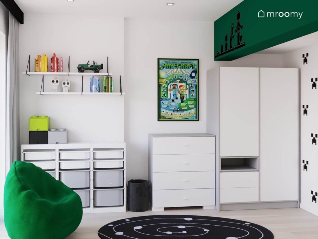 Białe meble zielona pufa kosmiczny dywan oraz plakat Minecraft w białym pokoju chłopca