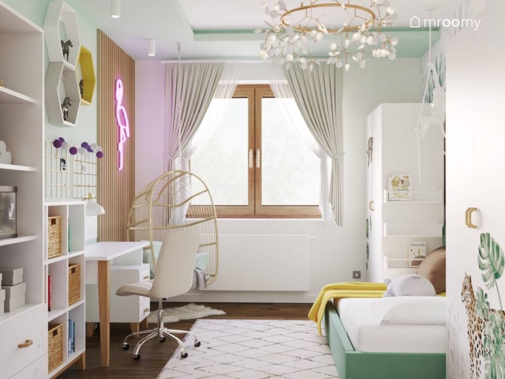 Jasny pokój dla dziewczynki a w nim białe meble zielonkawe łóżko fotel wiszący ledon flaming oraz ozdobna mosiężna lampa