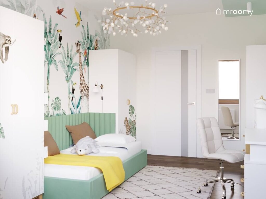 Białe szafy z naklejką w kształcie leniwca i jaguara zielone łóżko oraz ozdobna mosiężna lampa w pokoju dziewczynki w wieku szkolnym