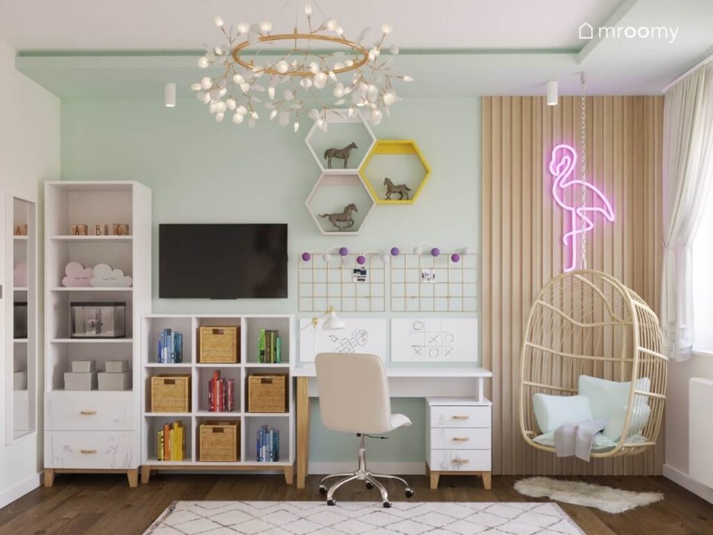 Zielona ściana w pokoju dziewczynki a na niej wysoki i kwadratowy regał telewizor biurko z organizerami sześciokątne półki i ledon w kształcie flaminga na panelach