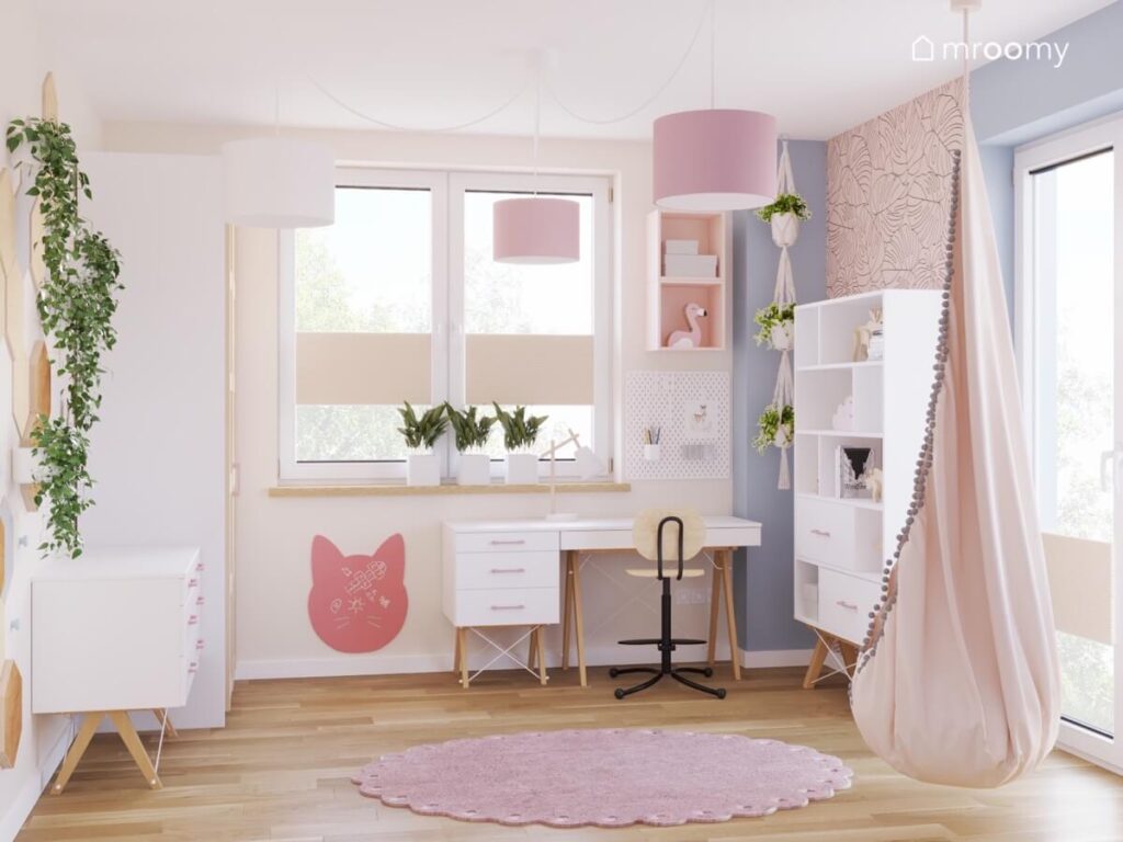 Jasny pokój dla dziewczynki z białymi meblami na drewnianych nogach fotelem kokonem tablicą kredową kot oraz różowym dywanem