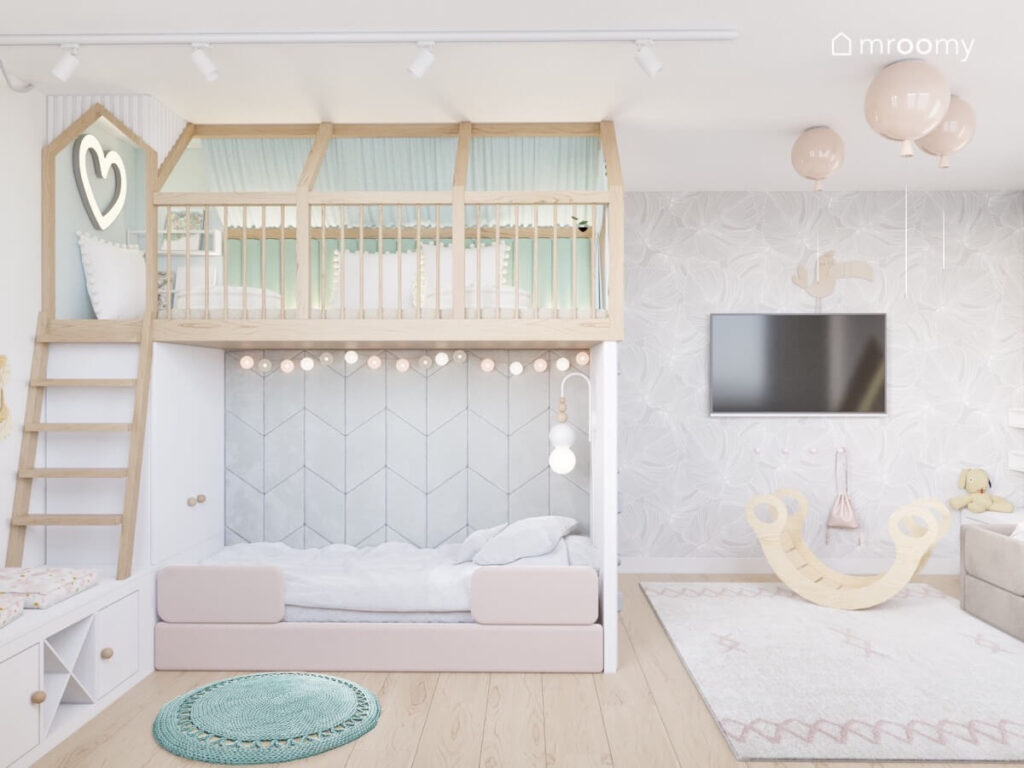 Drewniana antresola z miejscem do zabawy uzupełniona girlandą cotton balls a pod spodem łóżko na suficie lampy balony a na ścianie tapeta w liście w pokoju rodzeństwa