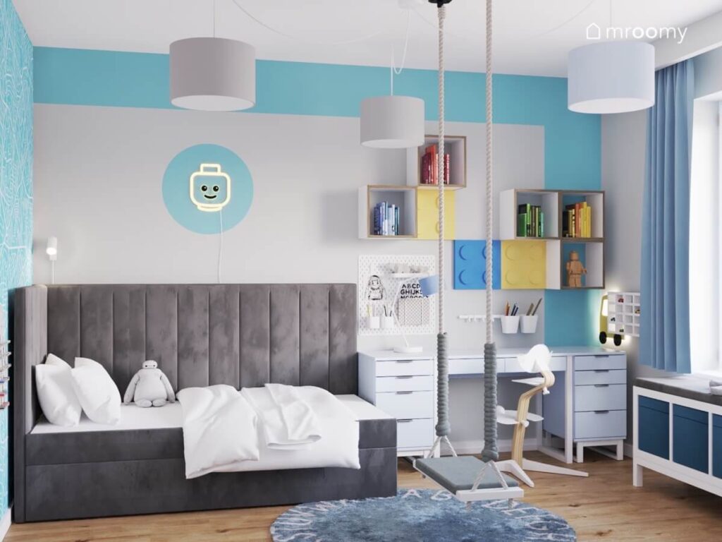 Szaro błękitny pokój dla chłopca z szarym tapicerowanym łóżkiem ledonem ludzikiem oraz huśtawką wiszącą i dywanem z alfabetem
