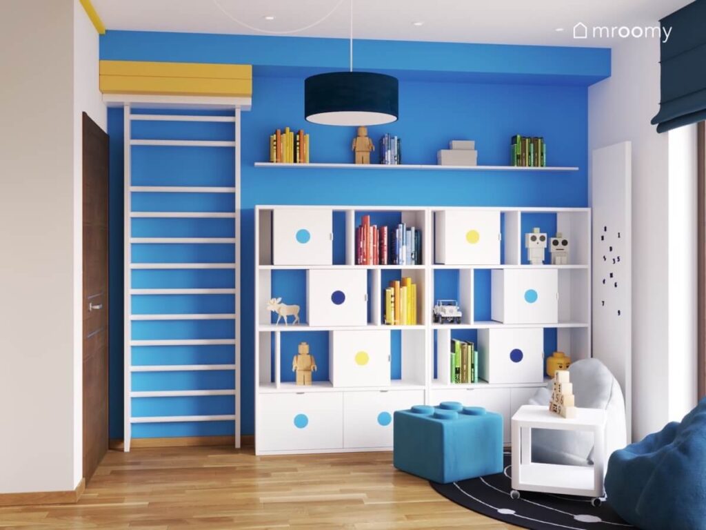 Niebieska ściana w pokoju chłopca a na niej drabinka gimnastyczna oraz dwa regały i półka