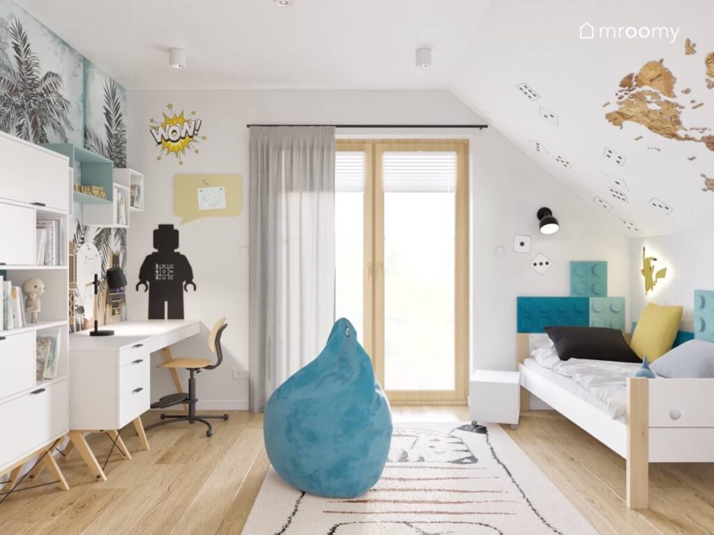 Biały poddaszowy pokój dla chłopca a w nim biało drewniane łóżko i meble panele ścienne w kształcie klocków oraz niebieska pufa