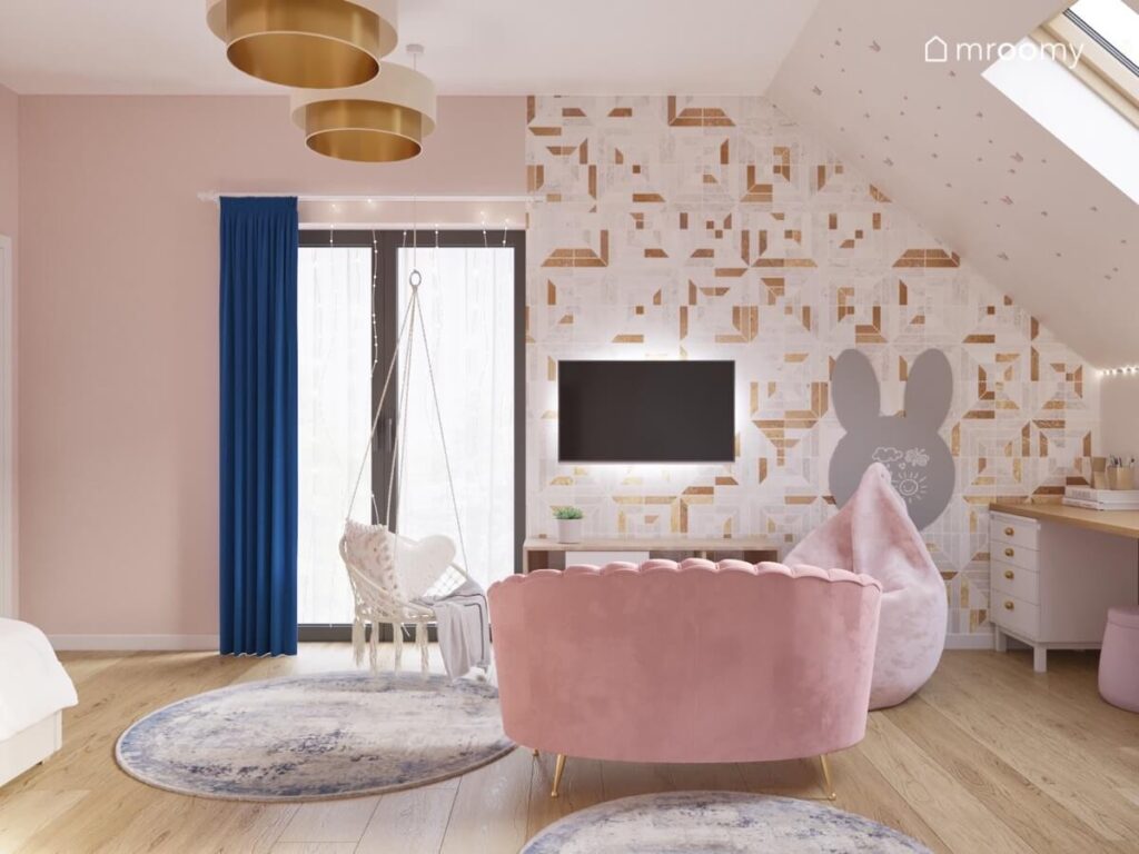 Jasny poddaszowy pokój dla dziewczynki z geometryczną tapetą fotelem wiszącym różową sofą oraz okrągłymi dywanami