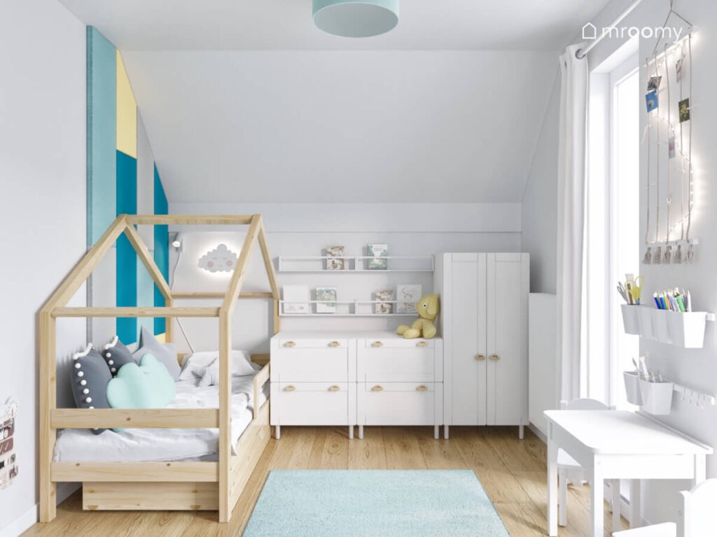 Biały poddaszowy pokój dla dzieci z drewnianym łóżkiem domkiem oraz białymi meblami z gałkami w kształcie samochodów