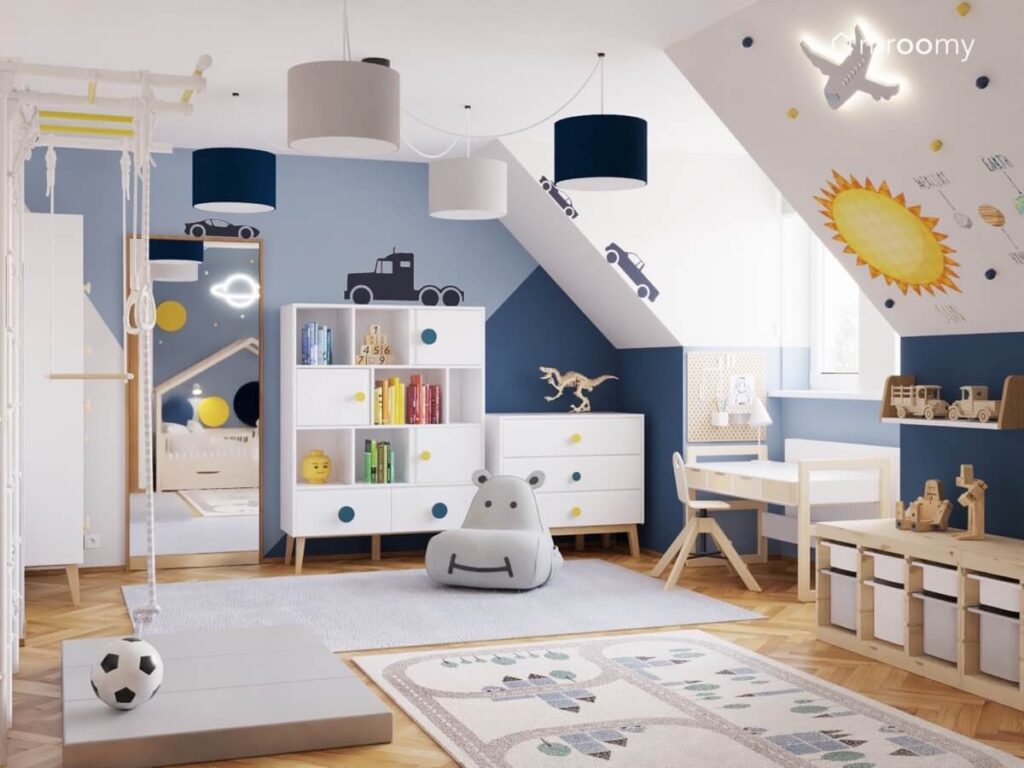 Poddaszowy pokój dla chłopca z białymi i drewnianymi meblami kosmicznymi i motoryzacyjnymi dodatkami oraz fotelem hipopotam