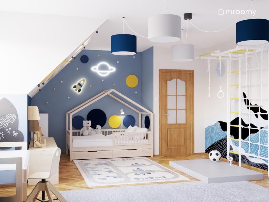 Biało niebieski pokój dla chłopca z łóżkiem domkiem drabinką gimnastyczną i dywanem z miastem a także kosmicznymi dodatkami