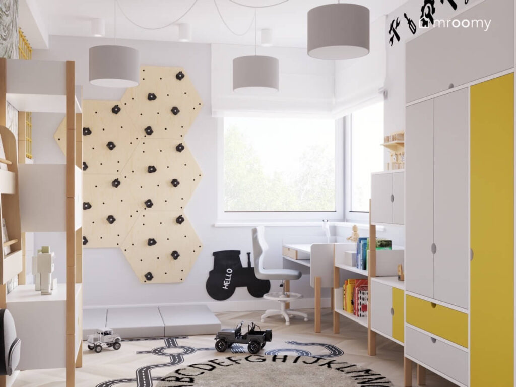 Jasnoszary pokój dla chłopca z panelami wspinaczkowymi tablicą kredową traktor oraz dywanem z alfabetem i naklejką podłogową