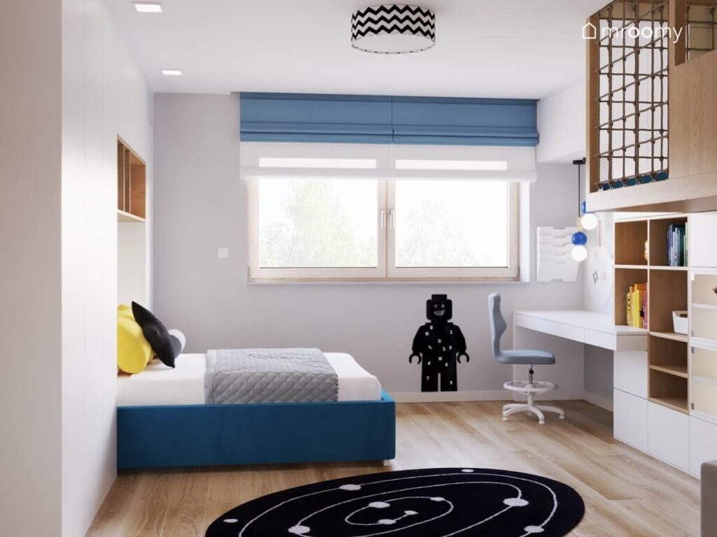 Biało szary pokój dla chłopca z niebieskim łóżkiem i białymi meblami oraz kosmicznym dywanem