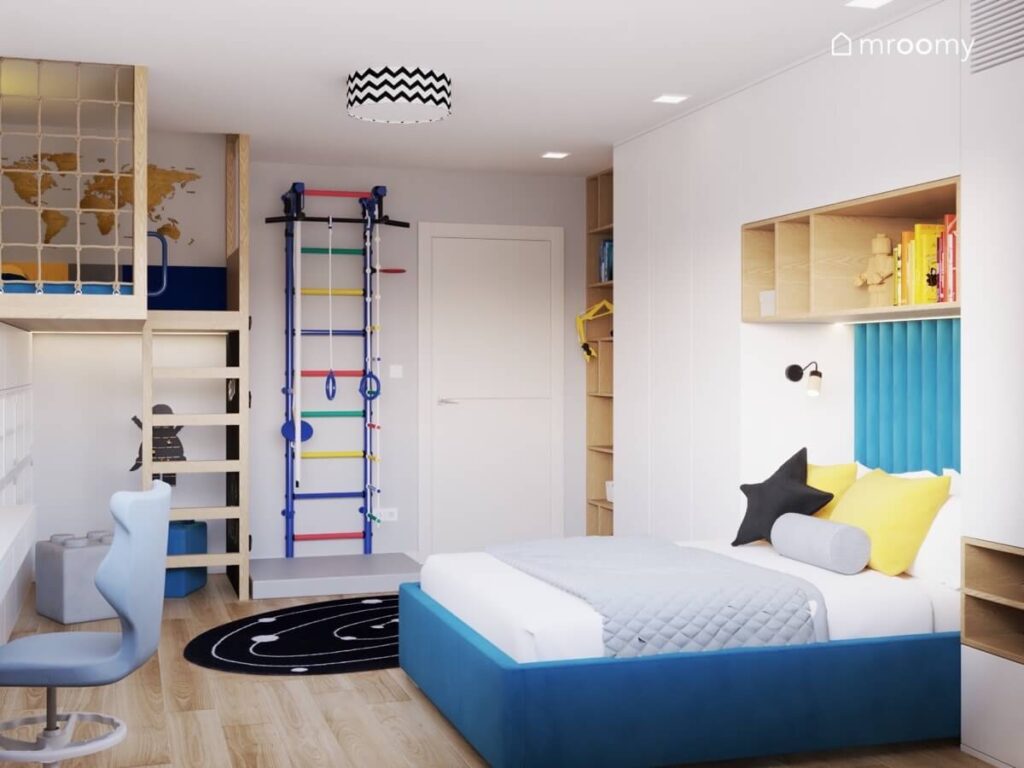 Niebieskie tapicerowane łóżko liczne drewniane półki oraz kolorowa drabinka gimnastyczna w pokoju chłopca