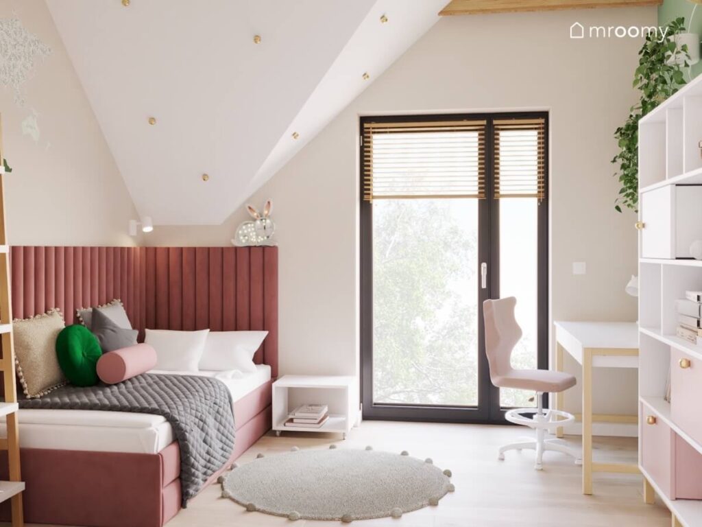Poddaszowy pokój dla dziewczynki z tapicerowanym łóżkiem prostym biurkiem i szarym dywanem oraz złotymi gałkami na skosie