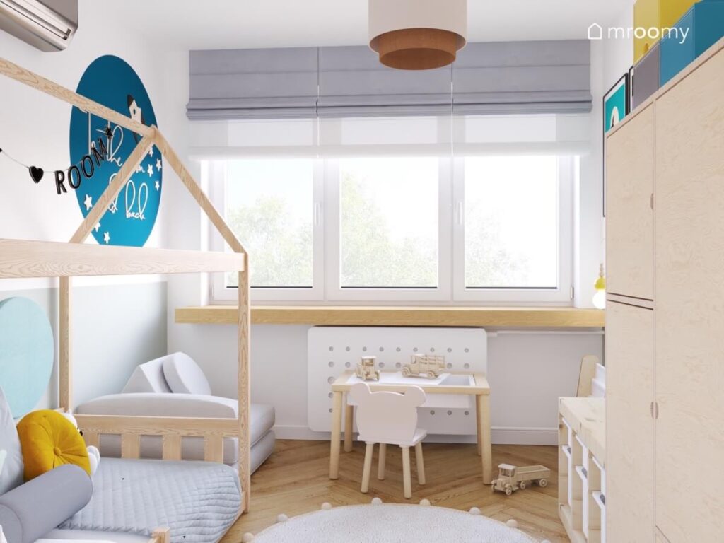 Jasny pokój dla chłopca z biało drewnianymi meblami oraz niebieskimi dodatkami