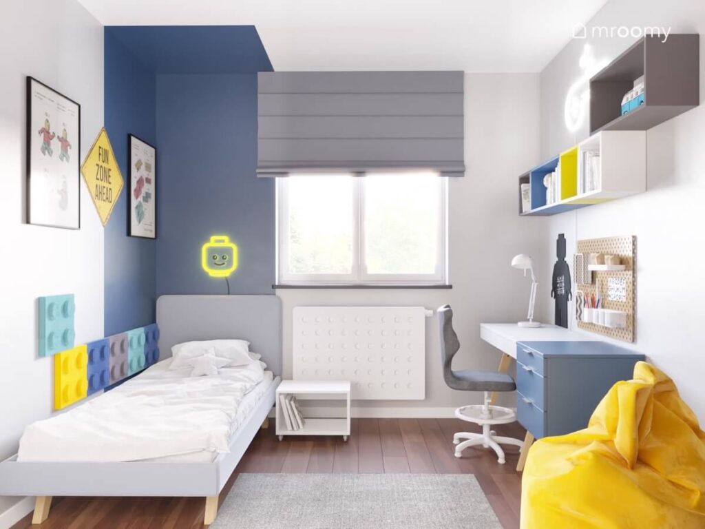 Szaro biały pokój dla chłopca z ciemnoniebieską strefą spania oraz żółtą pufą i dodatkami z Lego