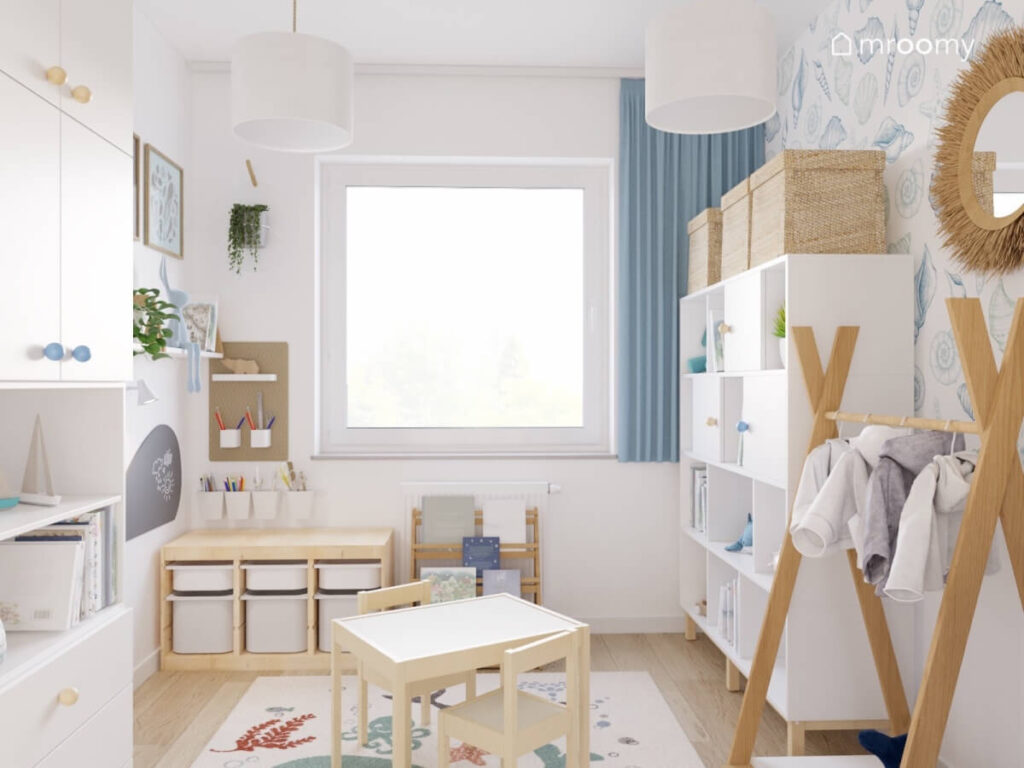 Biały pokój dla malutkiego chłopca a w nim biało drewniane meble dywan z morskimi stworzeniami oraz niebieska zasłona