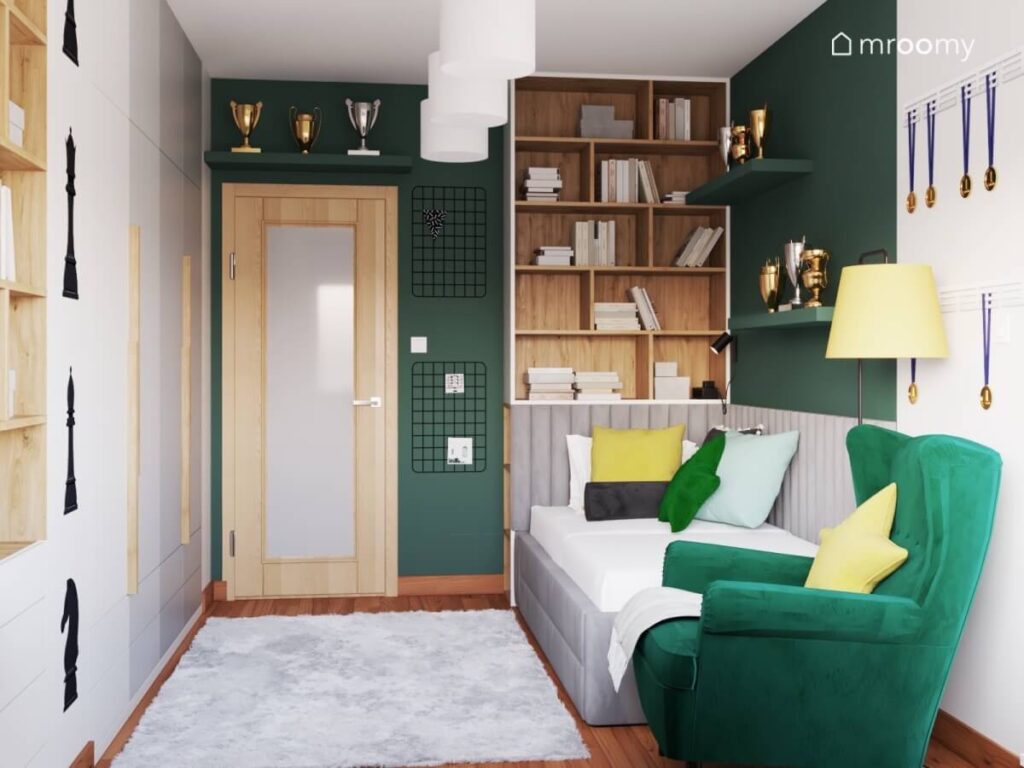Zielono biały pokój dla dziewczynki z szarym tapicerowanym łóżkiem zielonym fotelem drewnianym regałem puszystym dywanem oaz licznymi miejscami na puchary