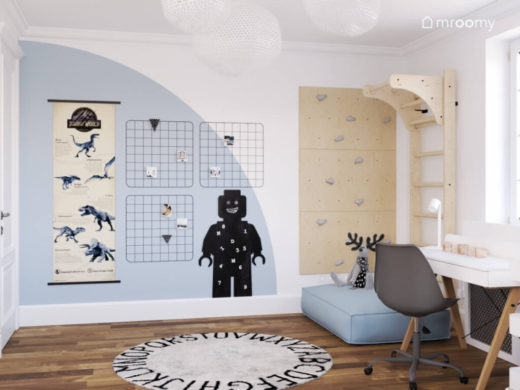 Biało niebieski pokój dla chłopca z dywanem z alfabetem organizerami tablicą kredową oraz plakatem z dinozaurami a także kącikiem sportowym