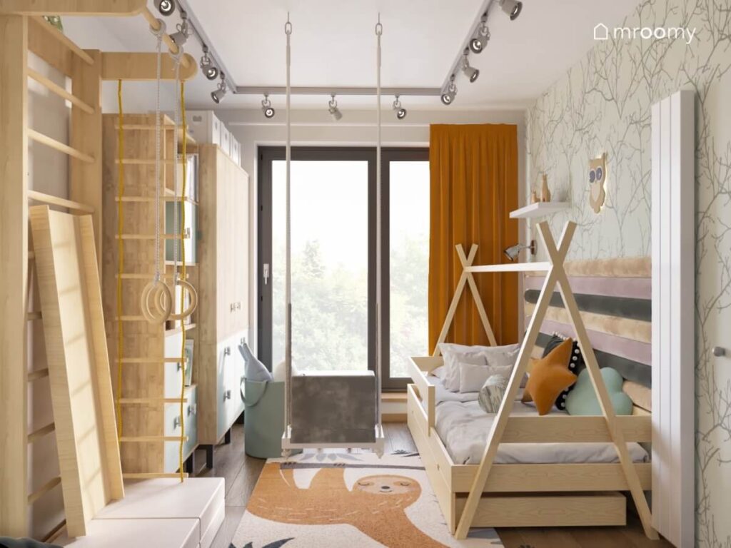 Przytulny pokój dla dziewczynki z drewnianymi meblami drabinką gimnastyczną huśtawką wiszącą oraz dywanem z leniwcem