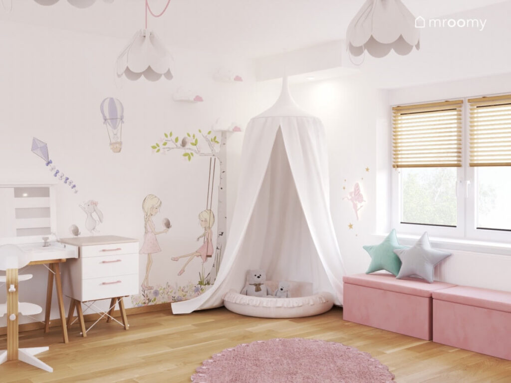 Gniazdko z baldachimem obok różowe siedziska a na ścianie tapeta z dziecięcym wzorem a na suficie lampy bezy w pokoju dla dziewczynki