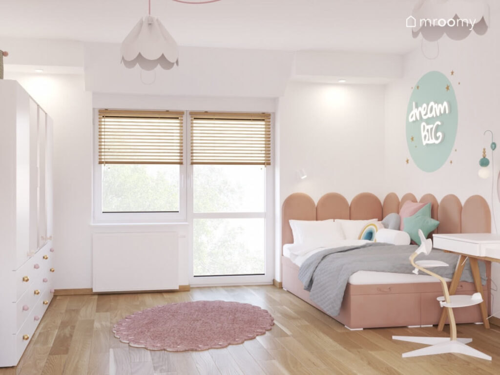 Biały pokój dla dziewczynki z tapicerowanym łóżkiem z panelami ledonem na ścianie oraz różowym dywanem