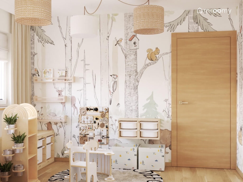 Ściana w pokoju chłopca pokryta leśną tapetą a na niej półki na książki regał z pojemnikami i zabawka sensoryczna