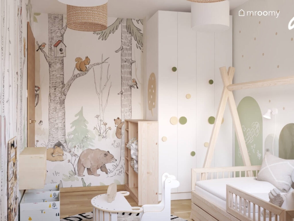Jasny pokój dla malutkiego chłopca a w nim białe i drewniane meble leśna tapeta oraz zielone dodatki