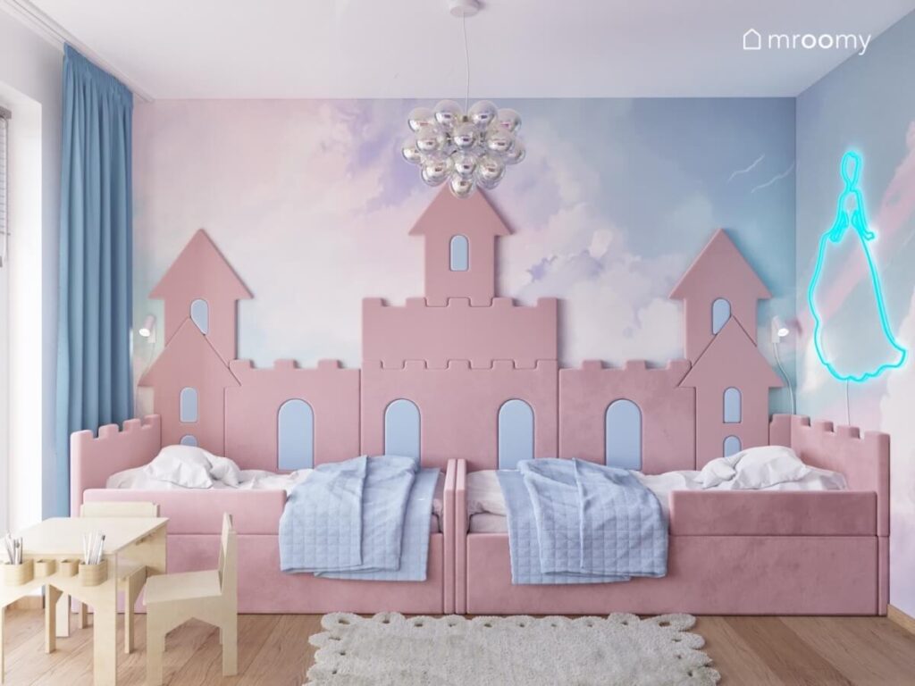Strefa spania w pokoju dwóch dziewczynek z różowymi tapicerowanymi łóżkami oraz zamkiem z miękkich paneli
