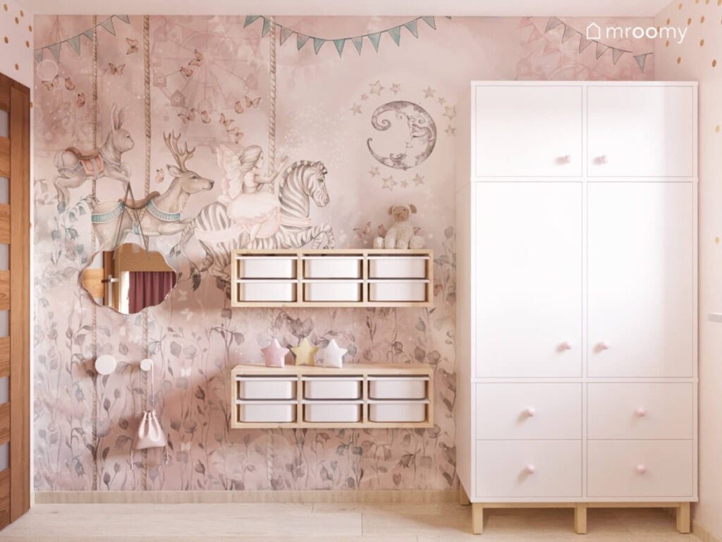 Ściana w pokoju dziewczynki pokryta piękną tapetą w zwierzęta a na niej lustro drewniane regały z pojemnikami oraz duża szafa