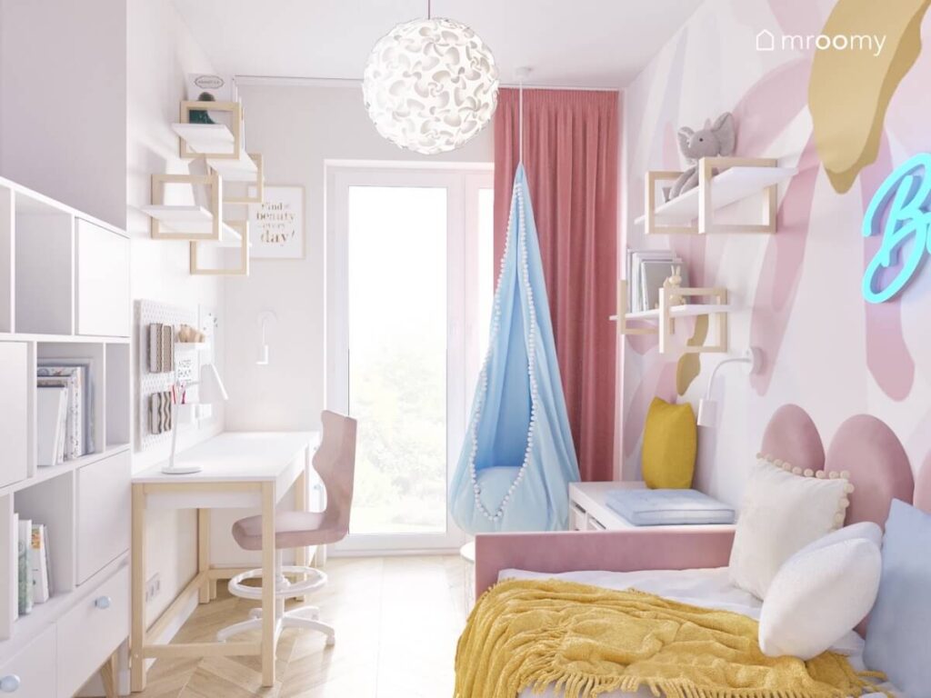 Jasny pokój dla dziewczynki z różowym łóżkiem niebieskim fotelem kokon oraz biało drewnianymi meblami