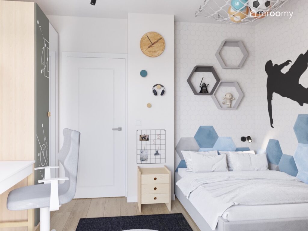 Strefa spania w pokoju dla chłopca a w niej łóżko uzupełnione panelami w kształcie heksagonów oraz półki ścienne w tym samym kształcie