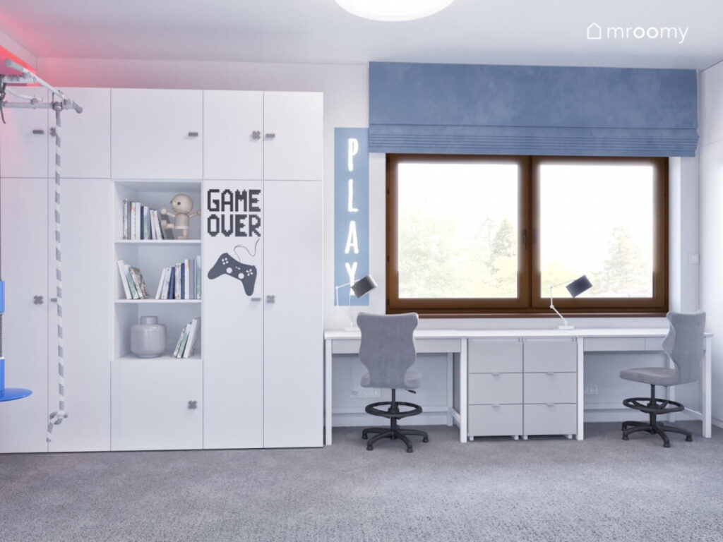 Biała szafa z naklejką gamingową a obok dwa biurka oświetlone ledonem w pokoju dwóch chłopców