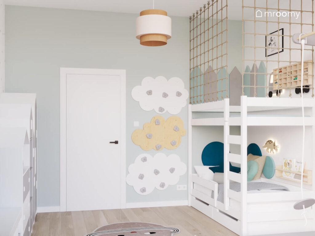 Panele wspinaczkowe w kształcie chmurek a obok łóżko piętrowe z miejscem do zabawy na górze w pokoju dla chłopca