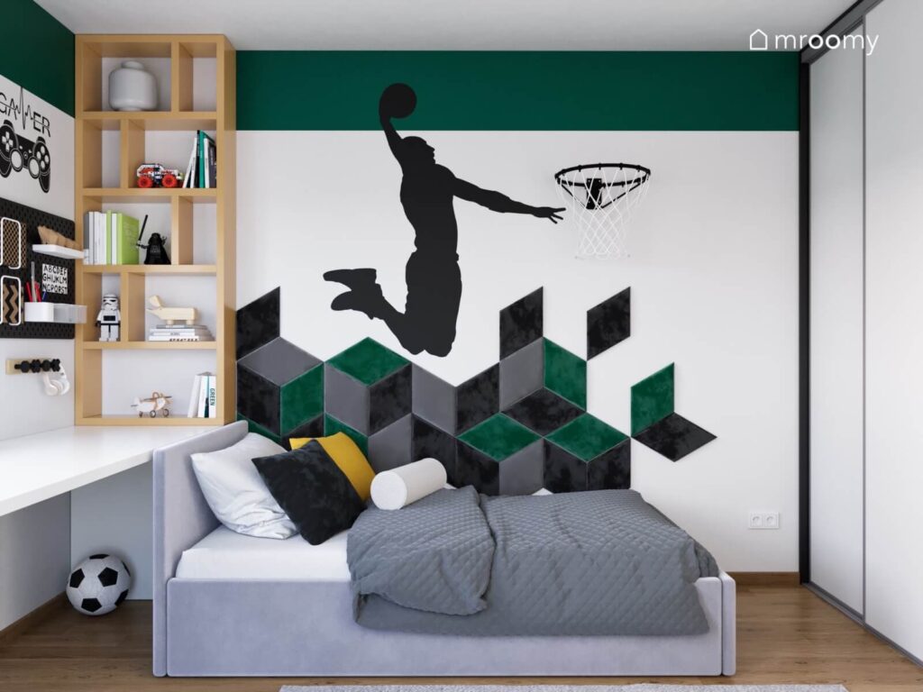 Szare tapicerowane łóżko w pokoju chłopca a na ścianie mozaika z miękkich paneli i naklejka z koszykarzem