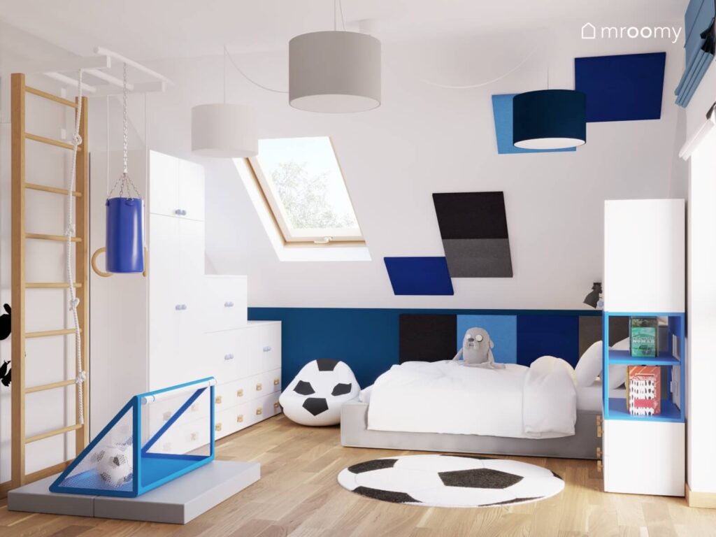 Biały poddaszowy pokój dla chłopca z białymi meblami szarym łóżkiem drabinką gimnastyczną i niebieskimi akcentami