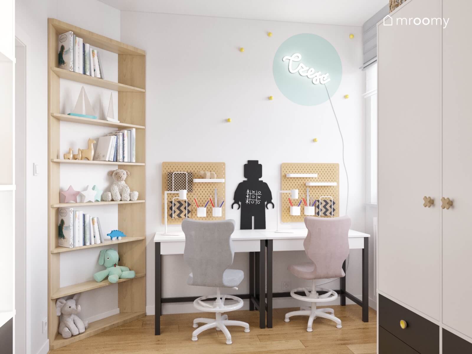 Strefa nauki w pokoju dla rodzeństwa z bliźniaczymi biurkami i organizerami tablicą kredową w kształcie ludzika Lego oraz drewnianym regałem