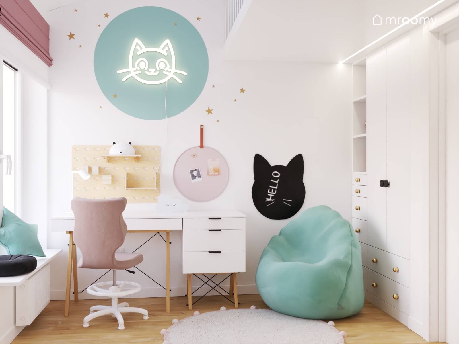 Strefa nauki w pokoju dziewczynki z biurkiem organizerami i tablicą kredową oświetlona przez ledon kot a obok niebieska pufa