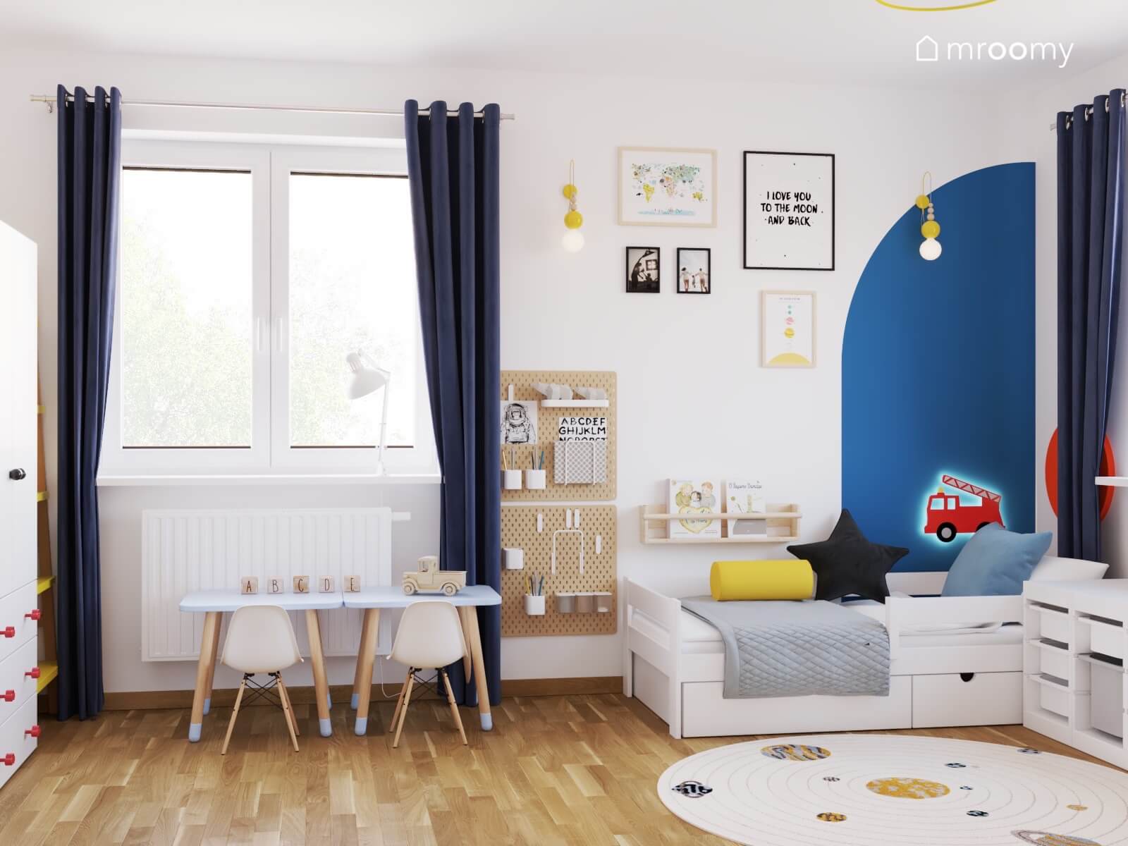 Biały pokój dla dwóch chłopców z organizerami na ścianach obrazkami w ramkach i białymi meblami