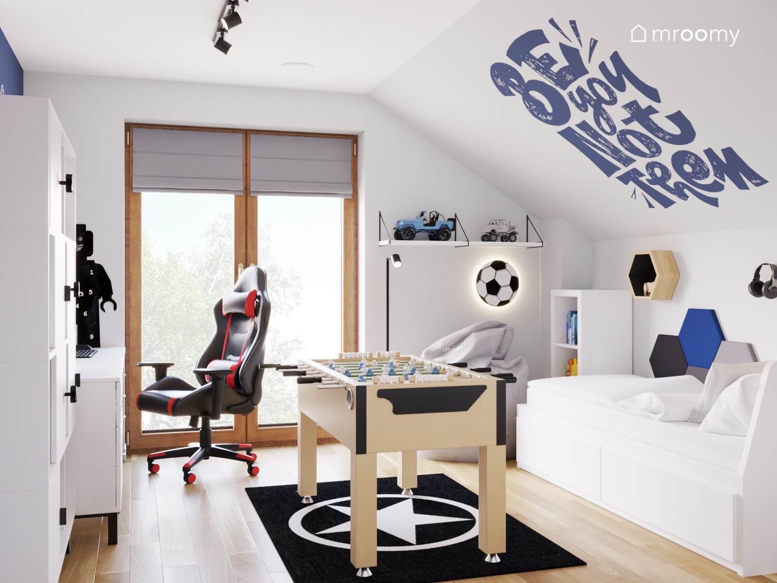 Jasny poddaszowy pokój chłopca z białymi meblami i stołem do piłkarzyków